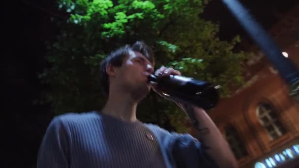 Opilý muž v svetr nápoje z láhve, má kus papíru a hodí daleko — Stock video