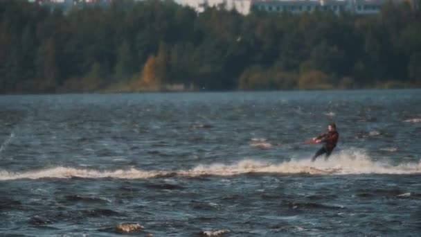 SAINT PETERSBURG, RUSSIA - 13 AGOSTO 2016: Uomo in giubbotto di salvataggio cavalcando wakeboard sul lago, tenendo in mano corda legata al jet ski — Video Stock