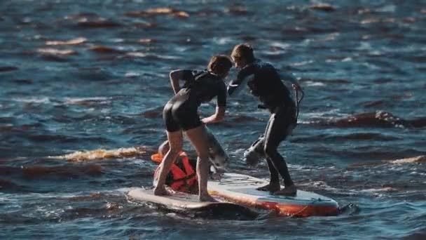 Saint Petersburg, Rusya - 13 Ağustos 2016: dalgalı suda sörf tahtası üzerinde duran yumuşak yarasalar ile mücadele iki kadın — Stok video