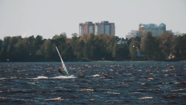 Petrohrad, Rusko - 13. srpna 2016: Muž v plavání oblek a život vestu jízdy wind surf na vlnité jezero vody — Stock video