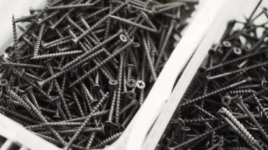 Büyük beyaz plastik kaplar uzun vida ve çivi dolu kamera gösterir.