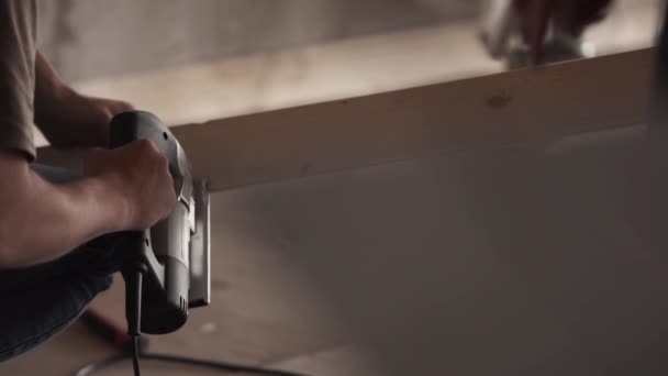 Males hands are using mechanical tool to wokk on wooden plank in workhouse. — Stock Video