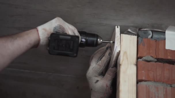 Αρσενικά χέρια στα γάντια χρησιμοποιούν μηχανική βίδα οδηγό να βίδα λεπτή ξύλινη σανίδα — Αρχείο Βίντεο