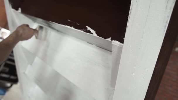 Руки работника мужского пола активно окрашивают серые стены в белый цвет большой кистью — стоковое видео