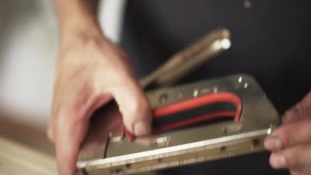 Mature males hands are holding staple gun and loading it with staples. — Stock Video