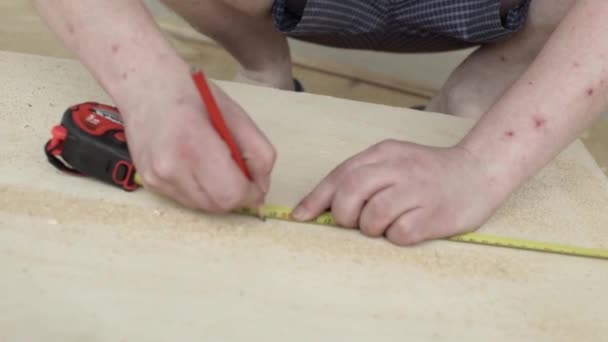 Mains de Mans avec règle jaune et crayon rouge faisant des marques sur la planche en bois — Video