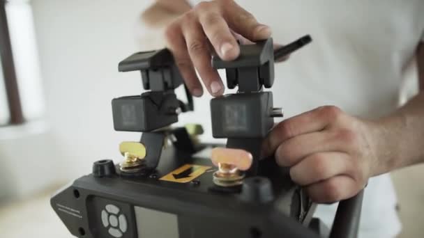 Руки хлопців встановлюють різні речі на чорному пластиковому пристрої в кімнаті — стокове відео