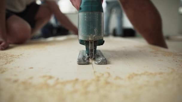 Arbeitsprozess der grünen staubigen elektrischen Stichsäge, die Holzplanken schneidet. — Stockvideo