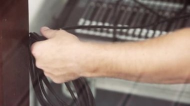 Adamın elleri elektronik in bulanık arka plan üzerinde siyah kablolar tutuyorsun.