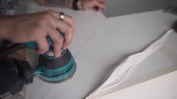 Mans hand is holding electronic green polisher and working on white surface. — Stock Video