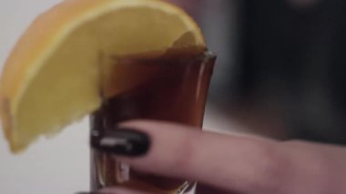 Kahverengi sıvı camına kadın el ile düzenlenen limonlu dökülür