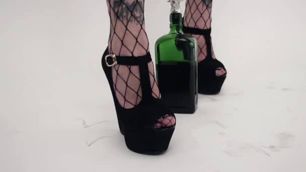 Kamera pokazuje womans nogi w pończochach w czarne buty z zielone butelki. — Wideo stockowe