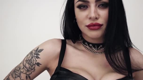 Cara de morena femenina vestida de cuero negro con labios grandes y maquillaje gótico — Vídeos de Stock