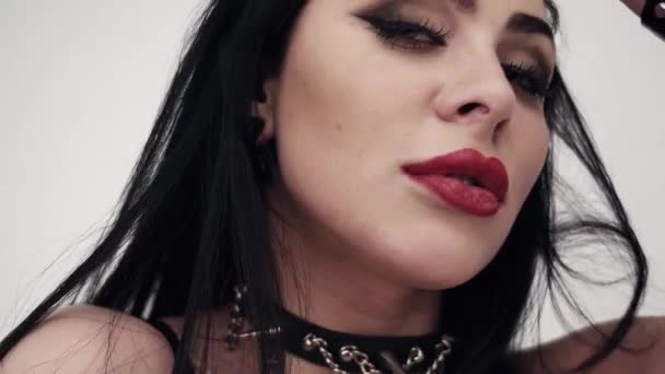 Ansikte av söt kvinna klädd i svart läder med stora läppar och gotiska makeup — Stockvideo