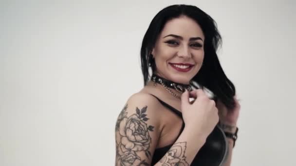 Mulher morena bonito vestindo couro com tatuagem no braço sorrisos na câmera . — Vídeo de Stock