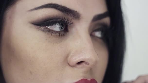 Mooi gezicht van vrouw met lange zwarte haren, grote lippen en schattige blauwe ogen. — Stockvideo