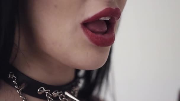 Nettes Mädchen mit sexy Lippen, großen blauen Augen, langen schwarzen Haaren und Make-up isst orange — Stockvideo