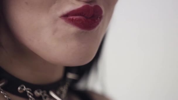 Frau mit sexy Lippen, großen blauen Augen, langen schwarzen Haaren und Make-up isst orange — Stockvideo