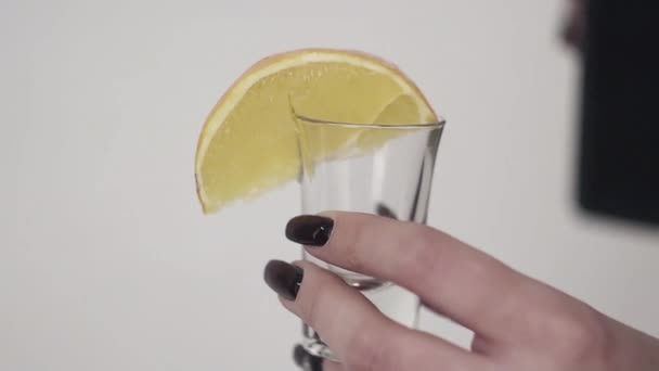 Bruine vloeistof is wordt gegoten op glas met citroen gehouden door dames hand — Stockvideo