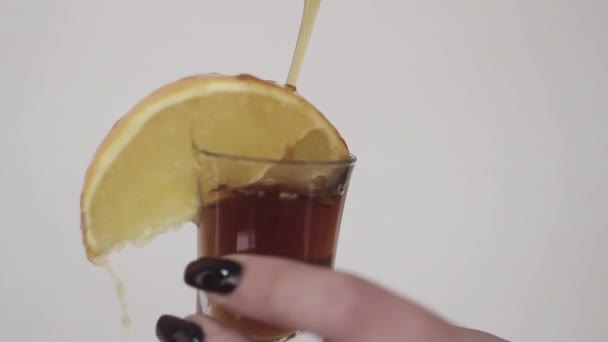 棕色液体被倒在杯子上, 用女人的手拿着柠檬 — 图库视频影像