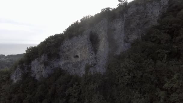 Εναέρια τοπία καταπράσινου λόφου με σπηλιά, Μαύρη θάλασσα, αμπχαζιανή shorecost — Αρχείο Βίντεο