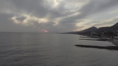 Uzun kıyı sahil hattı, yeşil hill büyük ağaçlar ve çalılar ile bulutlu gökyüzü günbatımı gösterilen ile güzel Karadeniz'in muhteşem manzara.