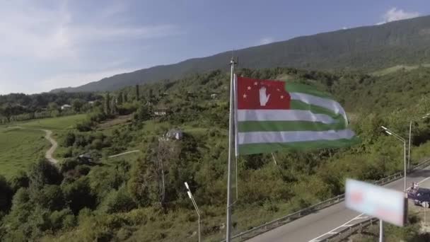 晴天在道路背景下, 在风中挥舞阿布哈兹旗帜的空中 — 图库视频影像