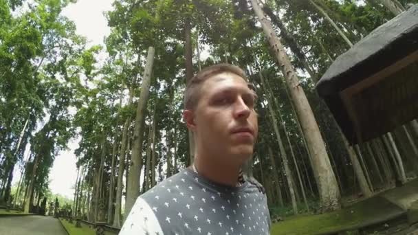 Kaukasiska kille står i parken med apa på sin axel som hoppar från honom — Stockvideo