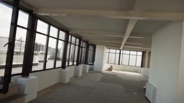 Büyük siyah çerçeveli pencereler ve beyaz duvarlar ve tavan ile büyük boş salonu.