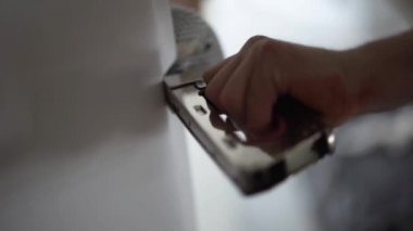 Profesyonel erkek ellerin ve elyaf silah bir yere yetimhane odasında kullanarak beyaz duvar kağıtları aktif sürüş ağır zımba.