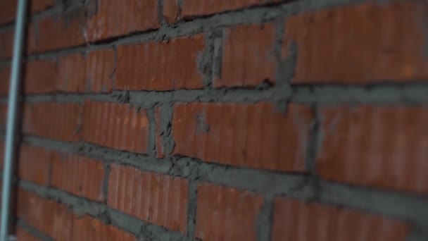 Kamera zeigt Wand mit roten Ziegeln und grauem Beton und Silhouetten von Männern. — Stockvideo