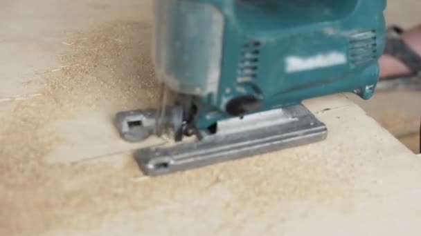 Demonstration of green dusty electric jigsaw cutting wooden plank. — Stock Video