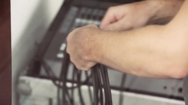 Hombres manos están sosteniendo cables negros en fondo borroso de material electrónico . — Vídeos de Stock