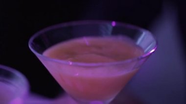 Closeup görünümü şık kokteyl gözlük soluk bir yerde gece kulübünde aydınlatma içinde tablo yerleştirilen alkol sıvı dolu.