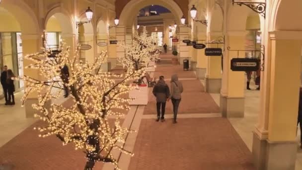 Торговая улица с подсвеченными желтыми зданиями магазинов и прогулка — стоковое видео