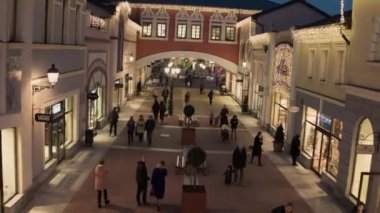 Işıklı sarı mağaza binaları ve yürüyen insanlarla rahat ışık sokak