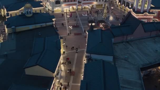 Drone visar mörka takåsar, lagra byggnader med belysning och vandrande folk — Stockvideo