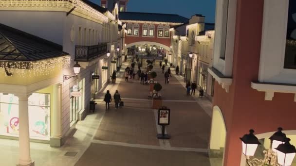 美丽的街道与被照亮的黄色商店大厦和步行的人 — 图库视频影像