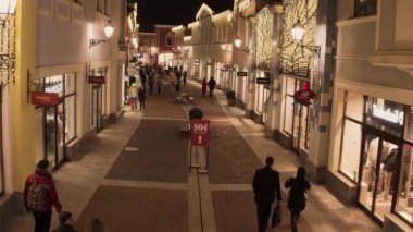 Işıklı sarı mağaza binaları ve yürüyen insanlarla rahat ışık sokak