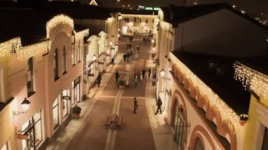 Işıklı sarı mağaza binaları ve yürüyen insanlarla rahat ışık sokak