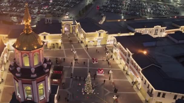 Ljusa byggnad med lysande gyllene kupol på lilla torget med julgran. — Stockvideo