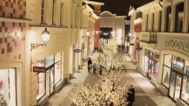 Işıklı sarı mağaza binaları ve yürüyen insanlarla rahat ışık sokak