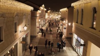 Işıklı sarı mağaza binaları ve yürüyen insanlarla rahat ışık sokak