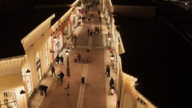 Işıklı sarı mağaza binaları ve yürüyen insanlarla rahat ışık sokak
