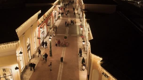 Rue lumineuse confortable avec des bâtiments de magasins jaunes éclairés et des personnes qui marchent — Video