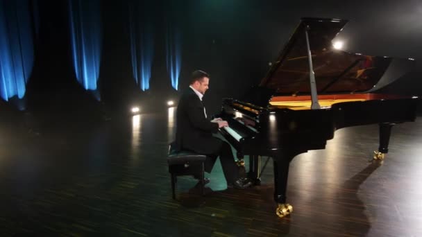 Pianista à moda antiga em terno e camisa toca piano de cauda preto no grande palco . — Vídeo de Stock