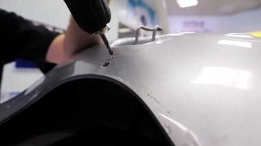 Vernikli plastik yüzey üzerinde delik açmak için elektronik tornavida adam kullanır