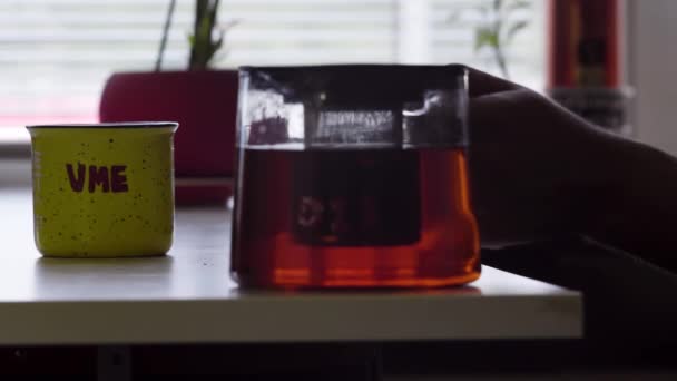 Камера показує стіл з великим кухоль і скляним чайним горщиком, повним звареного чаю напою . — стокове відео