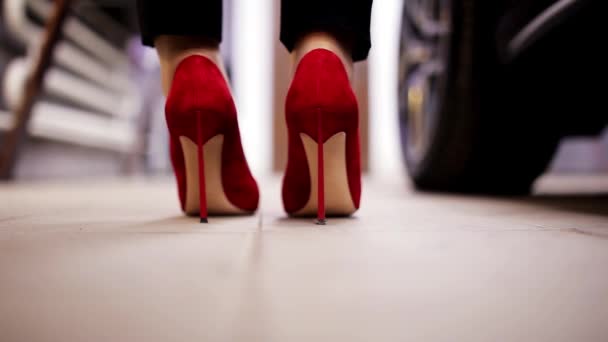 In garage woman dressed in red high heels gets out of car and walks away. — Stock Video