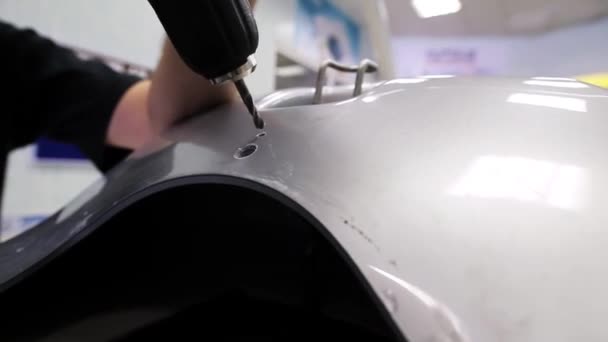 Man uses electronic screw driver to make hole on varnished plastic surface — Stock Video